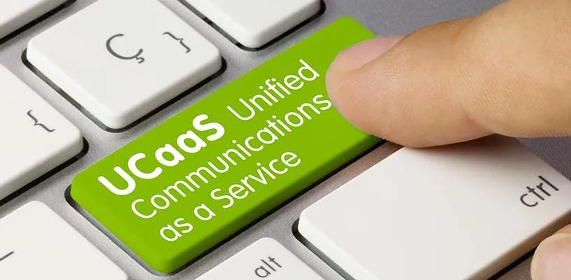Un dito preme un tasto verde della tastiera con la scritta UCaaS Unified Communications as a Service